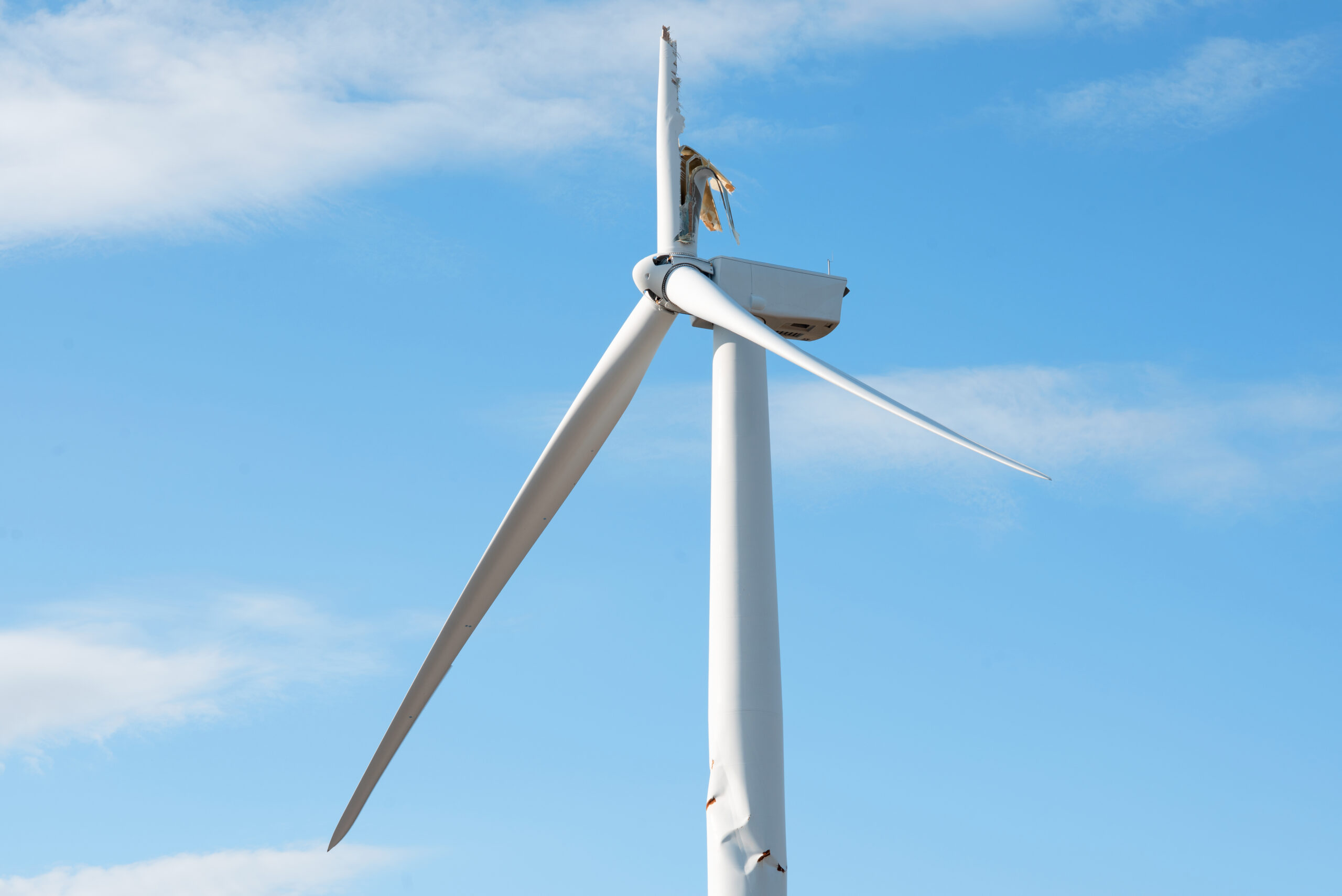 Electricity power wind turbine with broken blade and damaged tower awaiting repair after accident.