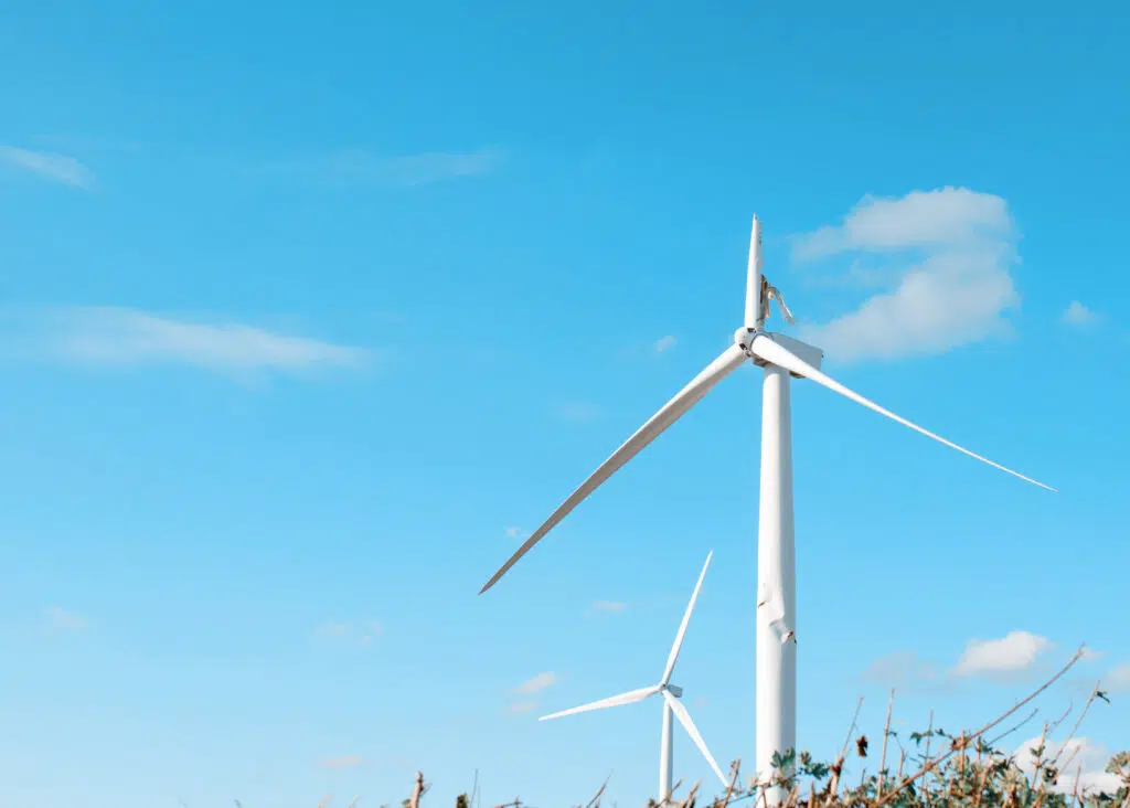 Wind turbine with broken blade not working and awaiting repair on a blue sky background