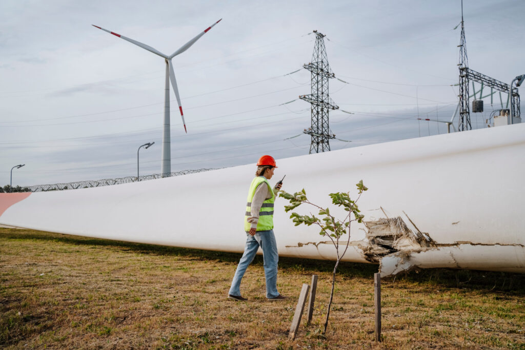 Engineer inspecting damaged blade of wind turbine at field